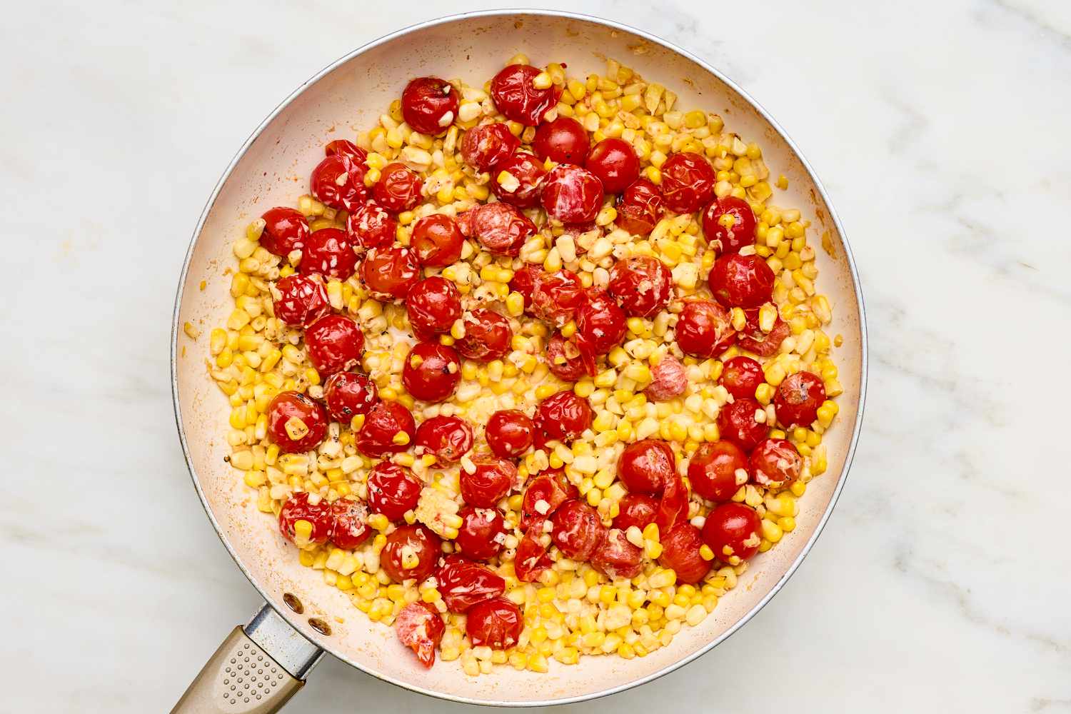 Heavy cream added to skillet with roasted tomatoes and corn kernels for Creamy Skillet Shrimp with Corn, Pancetta, and Tomatoes recipe