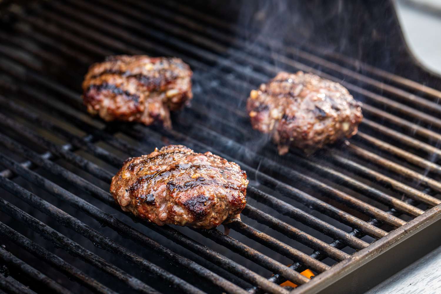 Perfect bacon cheeseburger patties cooking on the grill.