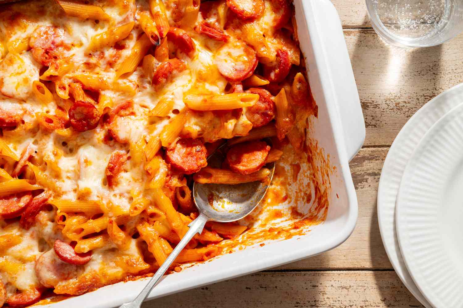Penne and Smoked Sausage Casserole in a baking dish with a serving spoon