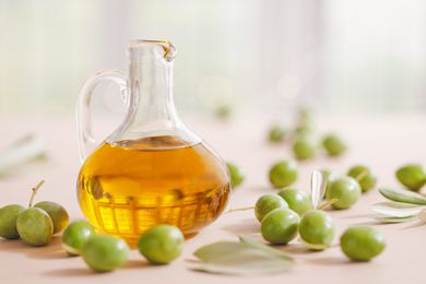 Green olives and olive oil in a glass cruet