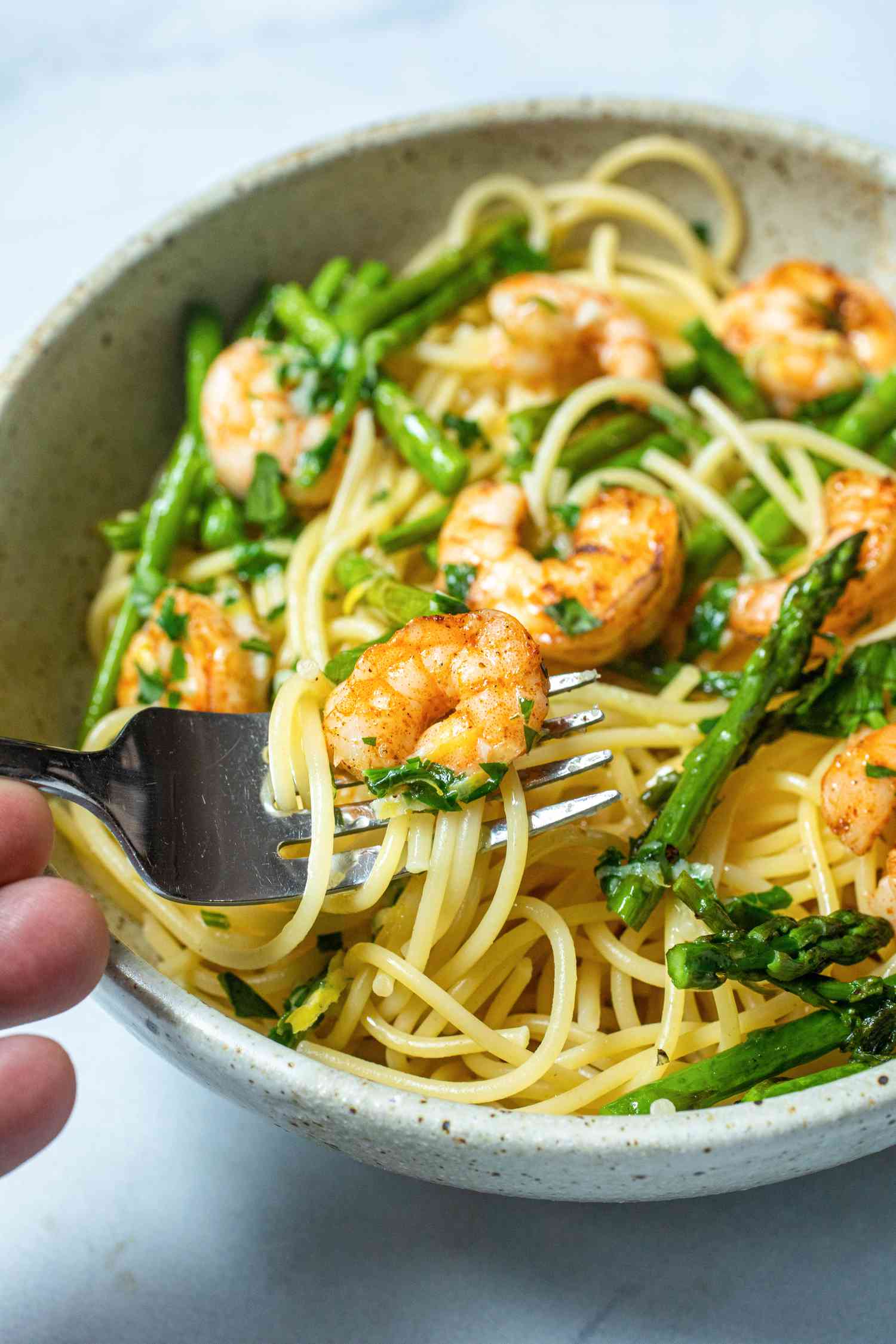 Sheet pan garlic butter shrimp with asparagus served in a bowl over pasta.
