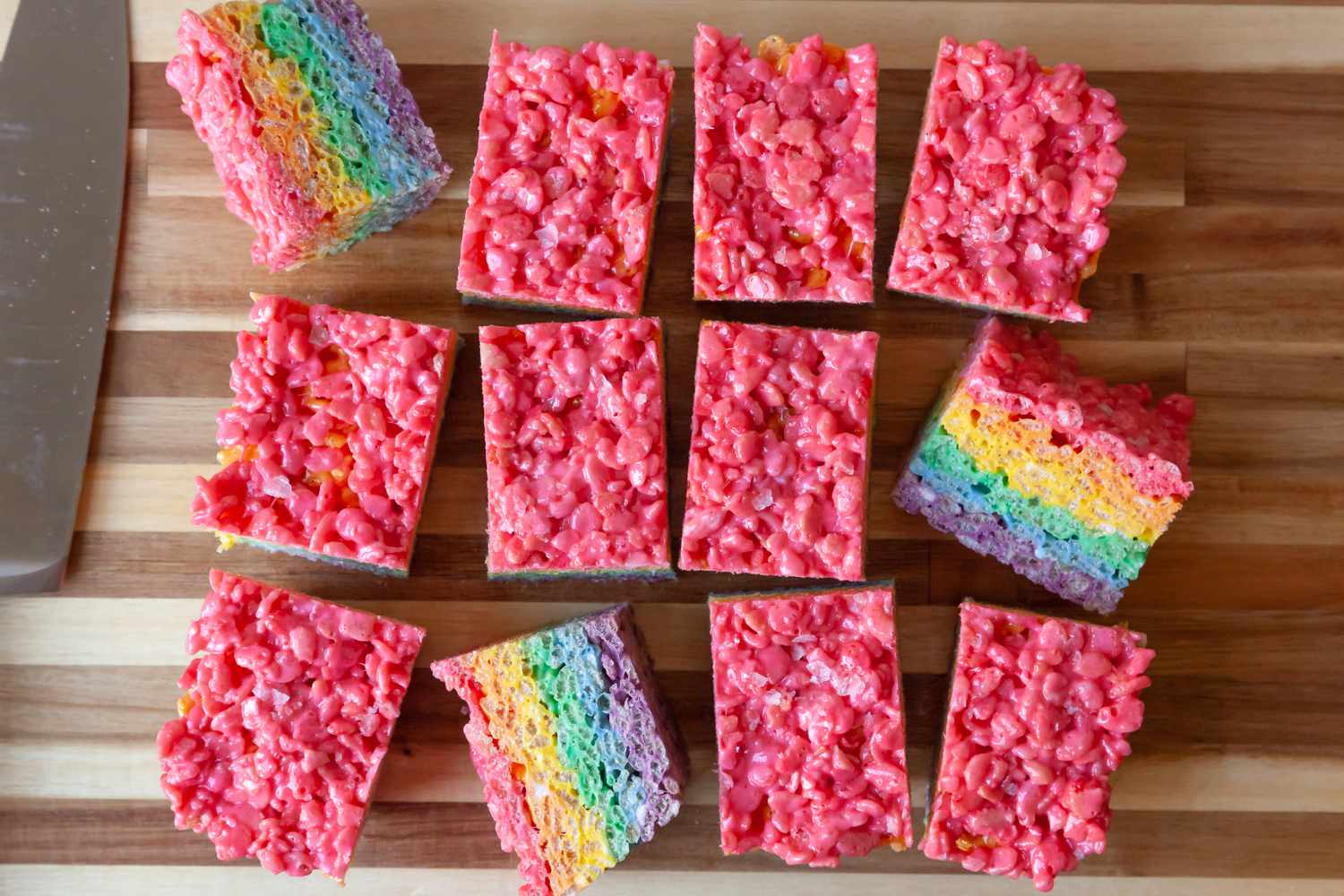 Rainbow Rice Krispie Treats on Cutting Board Cut into Twelve Pieces with Some on Its Side Showing Rainbow Colors