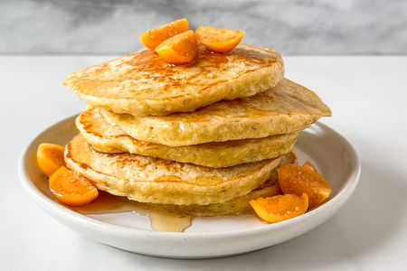 Stack of pancakes topped with sliced fruit