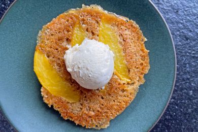 Peach upsidedown cookie topped with a scoop of ice cream on a plate
