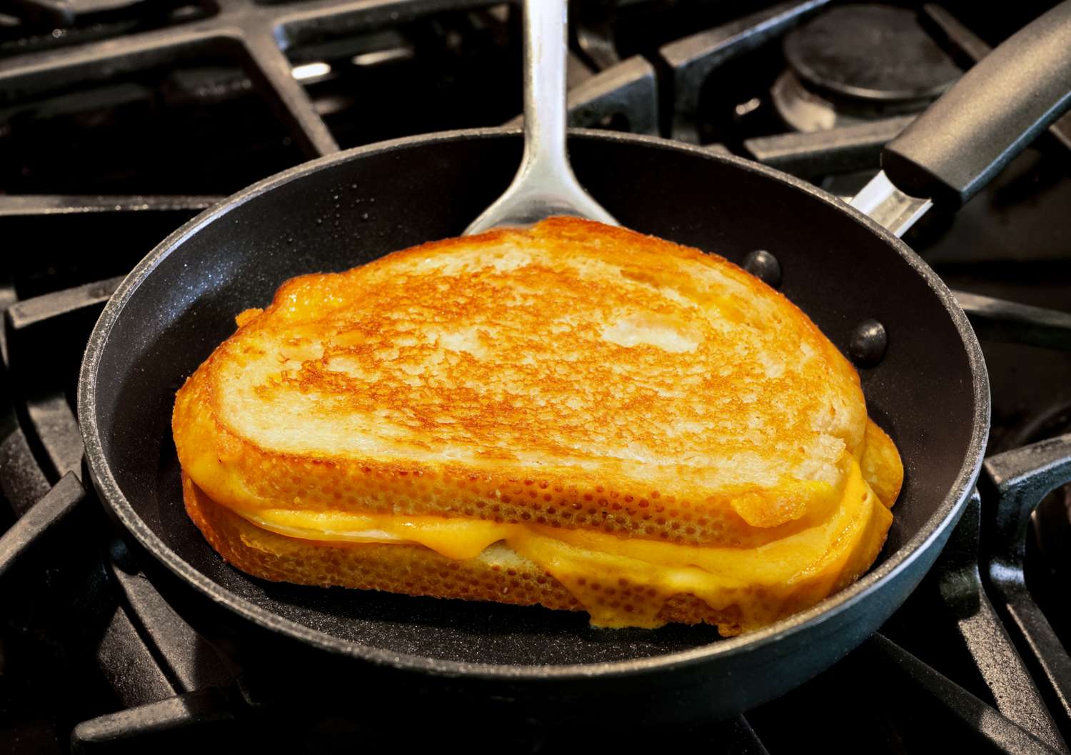 A grilled cheese sandwich cooking in a frying pan on a stovetop