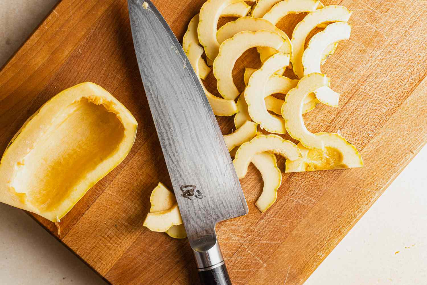 Delicata Squash Cut into Thin Slices on a Cutting Board for Pakoras Recipe