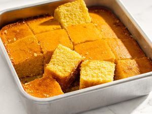 A square pan containing cut pieces of cornbread some pieces slightly raised