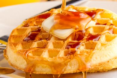 Eggo waffle topped with butter and syrup being poured