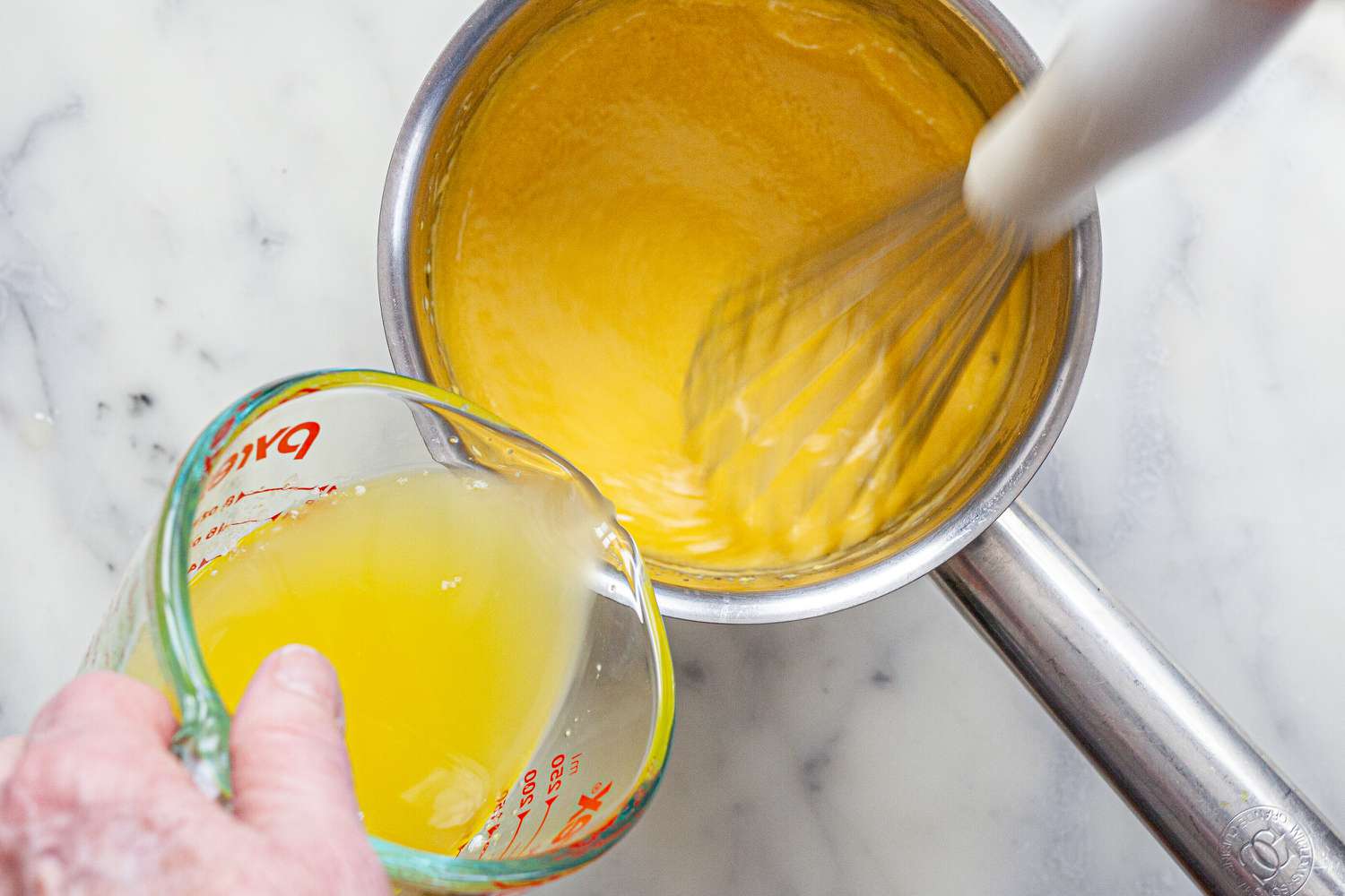 Adding clarified butter to the pot to show how to make béarnaise sauce.