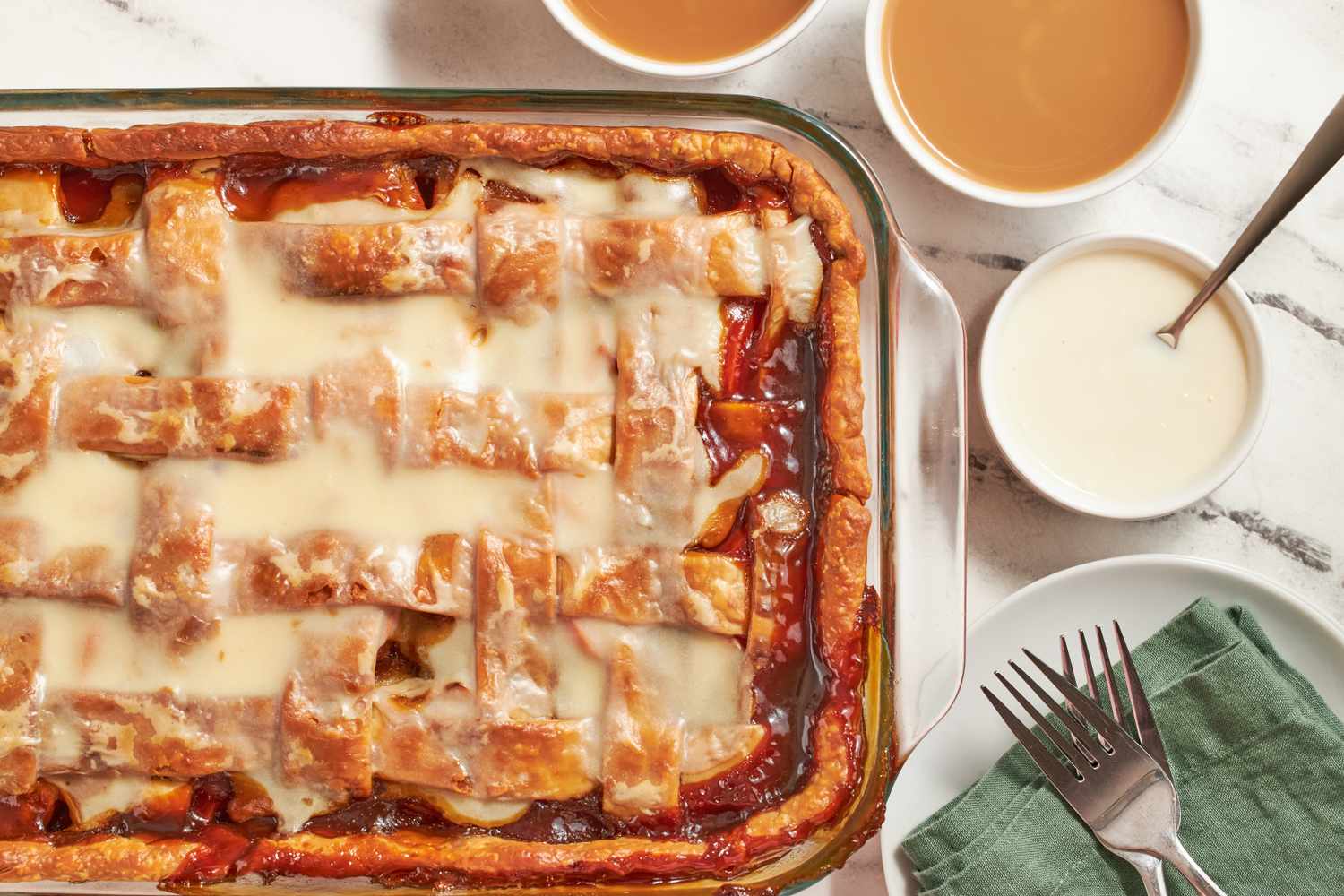 Dessert dish with lattice crust and two small bowls of sauce on a table