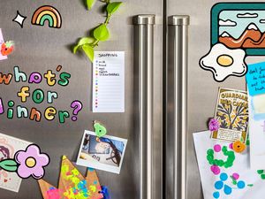 Refrigerator with decorations and notes including a shopping list and childrens artwork