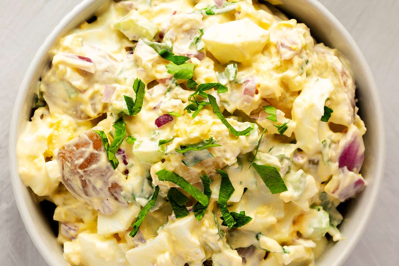 A bowl of creamy potato salad with garnished herbs