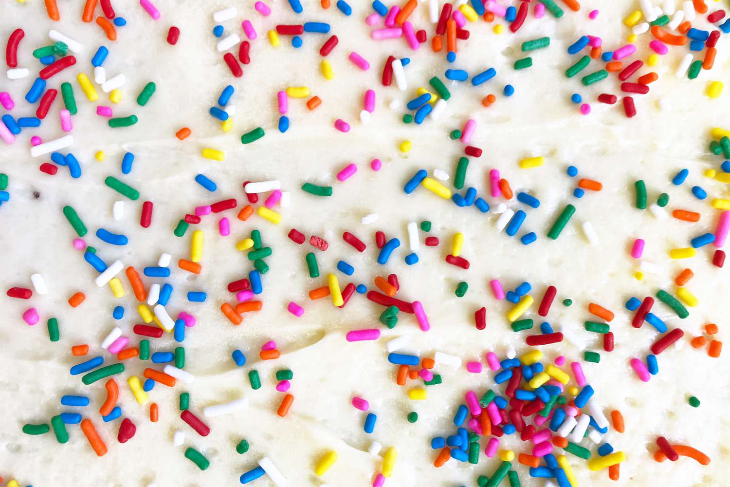 A close-up view of a white frosted cake decorated with colorful sprinkles