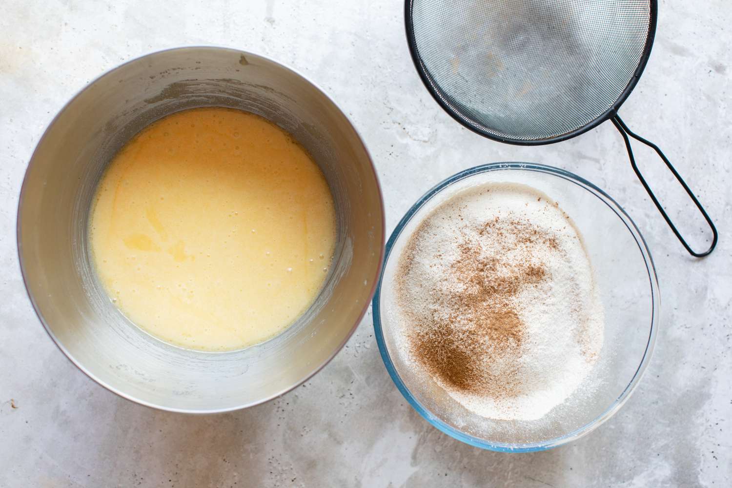 Two Bowls (One with Wet Ingredients and the Second with Sifted Dry Ingredients) Next to a Sieve for Fresh Apple Cake
