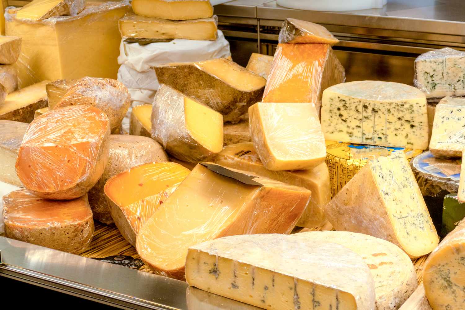 A cheese display featuring a variety of cheese wheels and blocks in a store