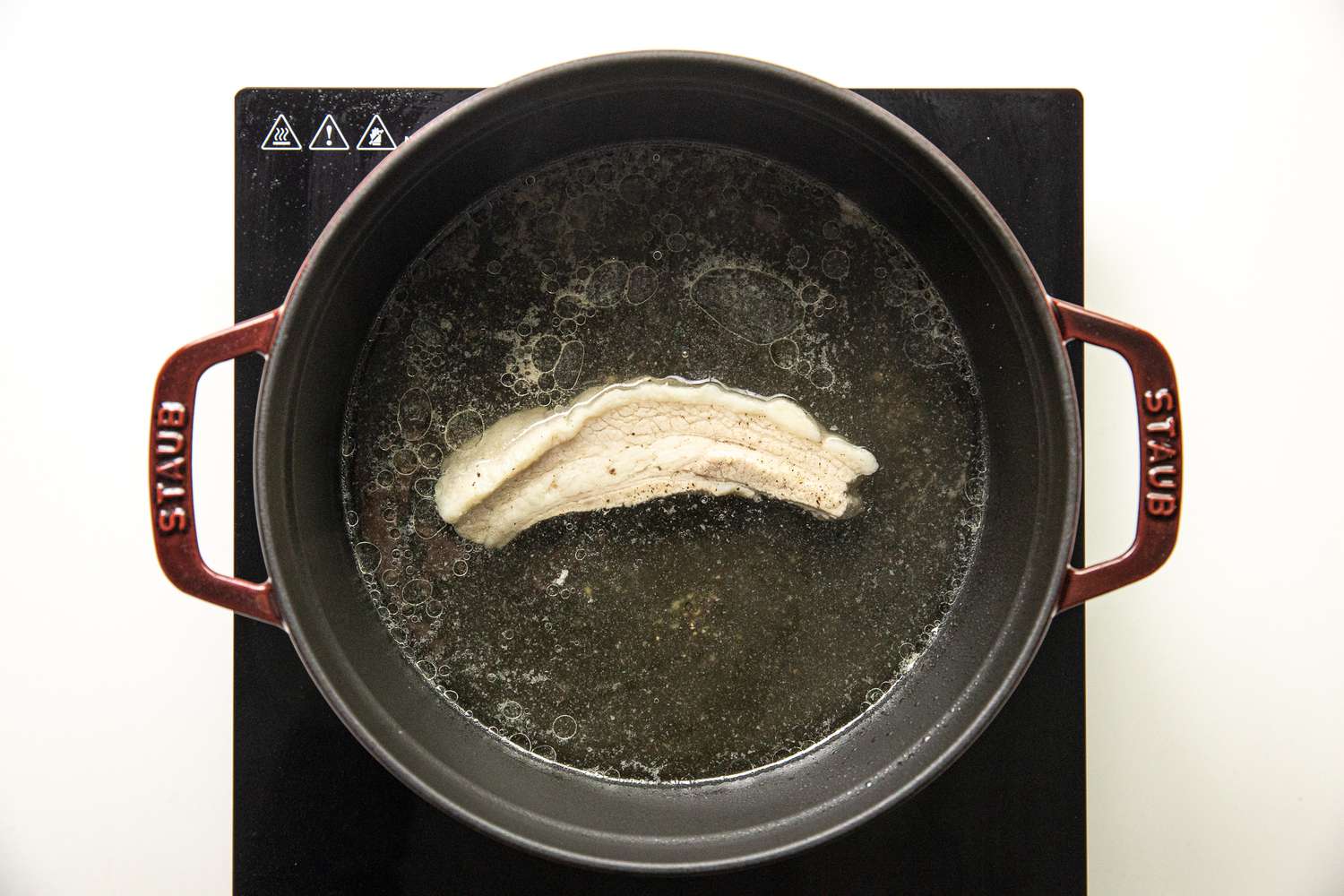 Slab of Pork Boiling in a Dutch Oven for Pancit Bihon Recipe