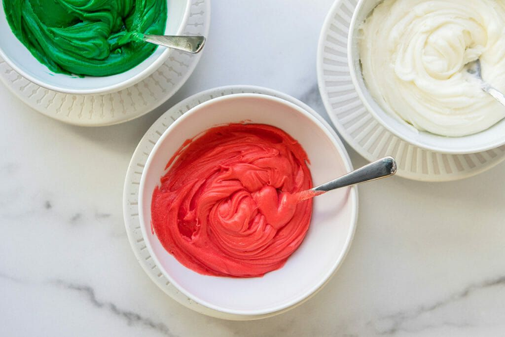 Individual bowls of red, green, and white sugar cookie icing.