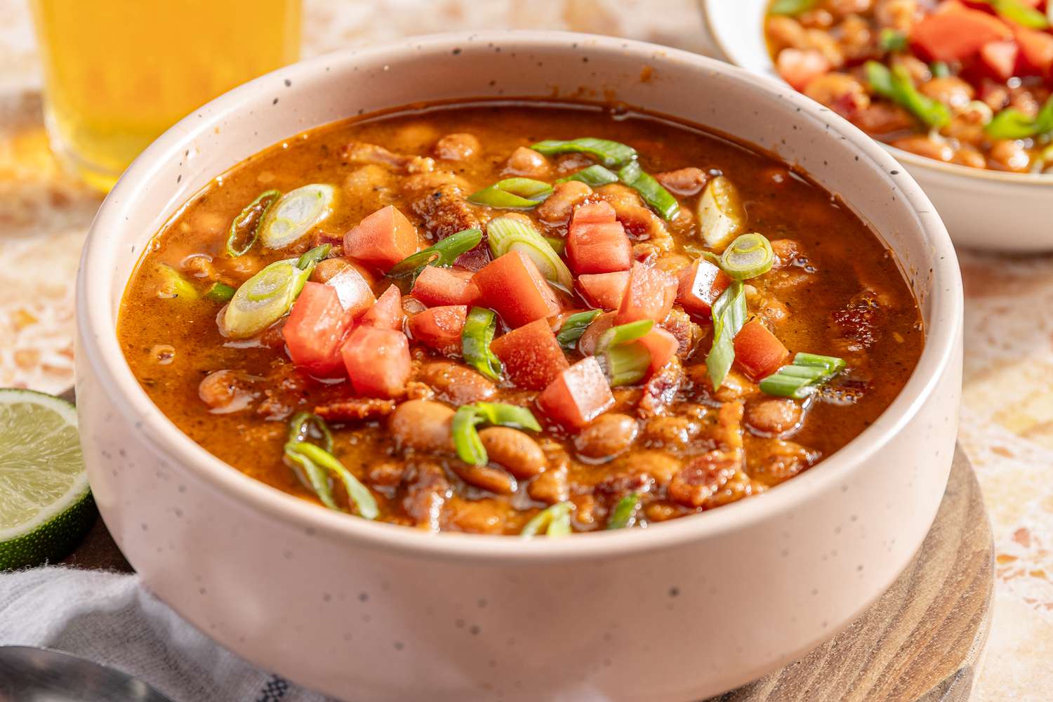 Side view of a bowl with chili, topped with fresh diced tomatoes and scallions