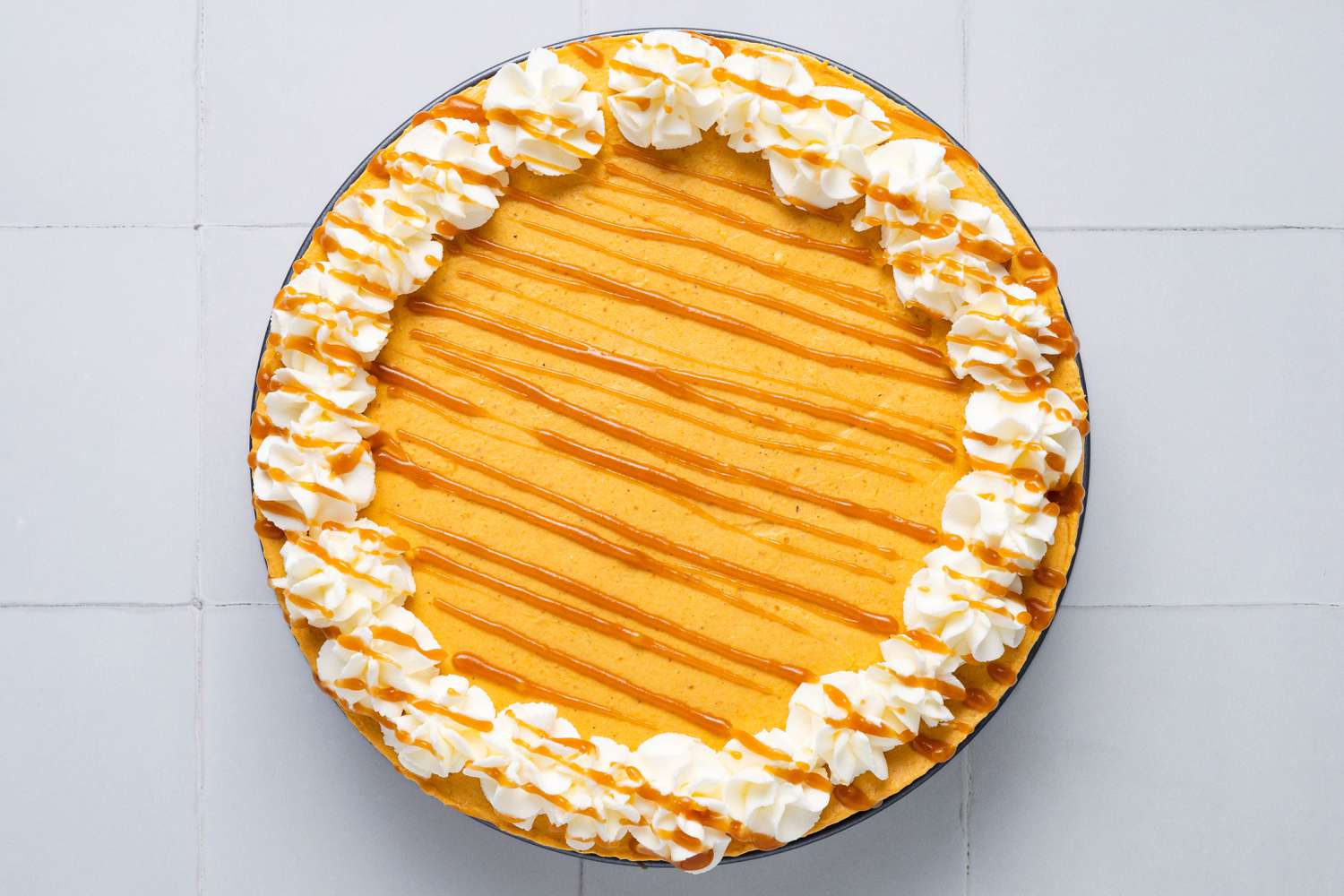No-bake pumpkin cheesecake topped with whipped cream rosettes and caramel sauce