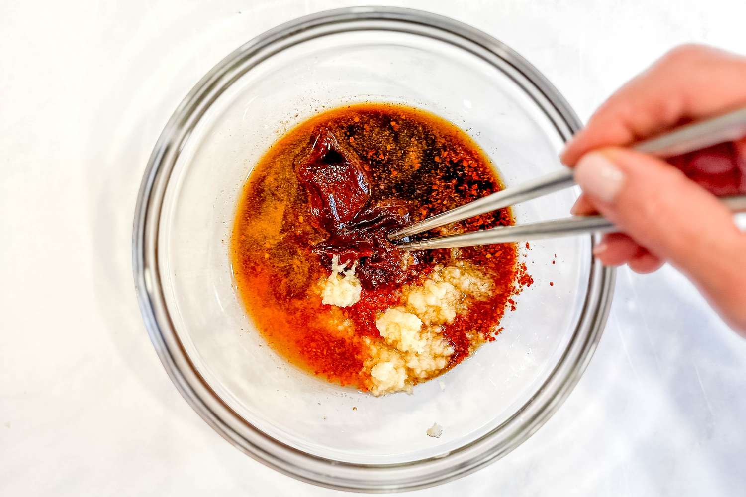 Budae jjigae sauce whisked together in a bowl using a pair of chop sticks