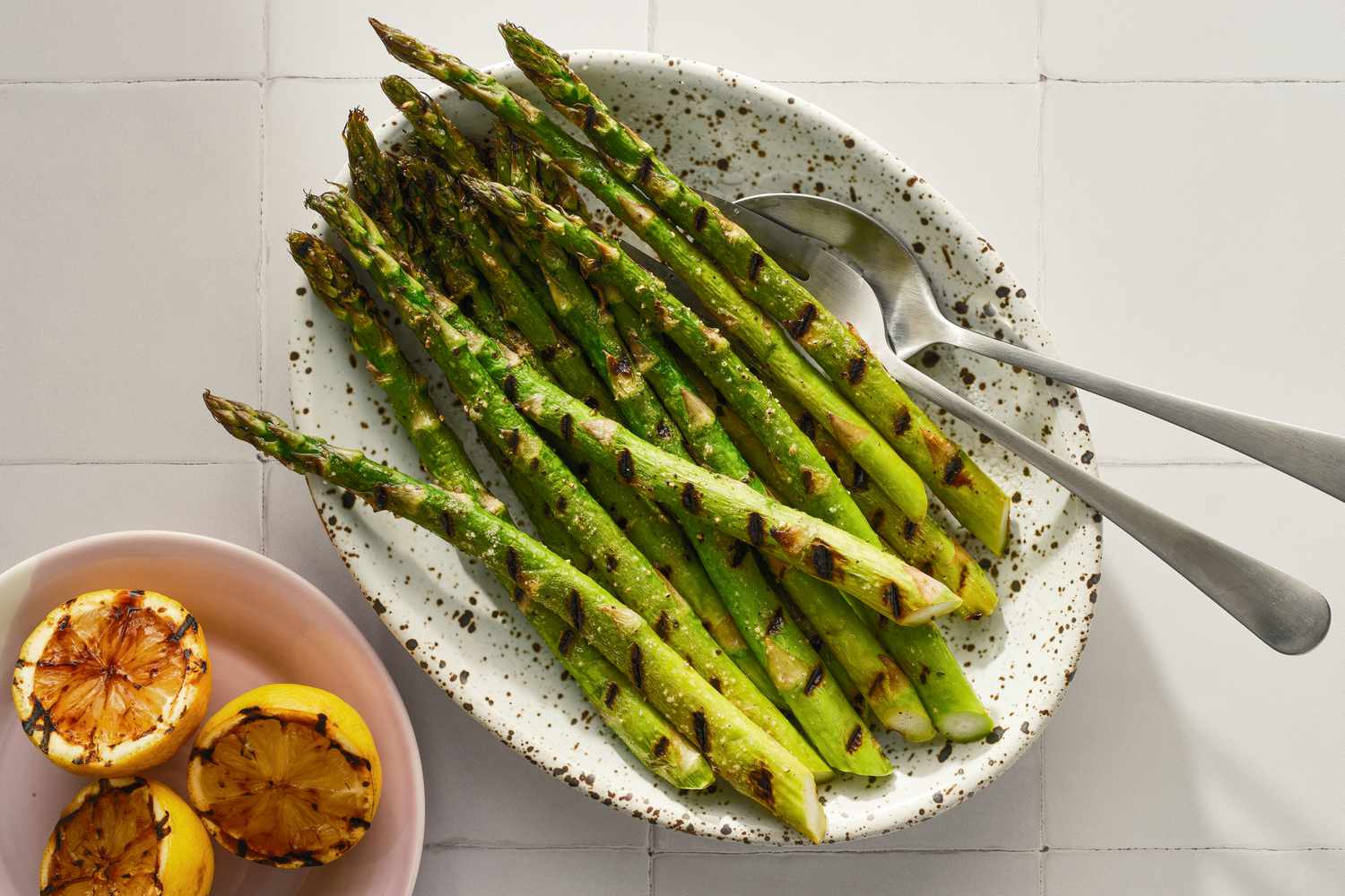 Platter of grilled asparagus with small plate of grilled lemons