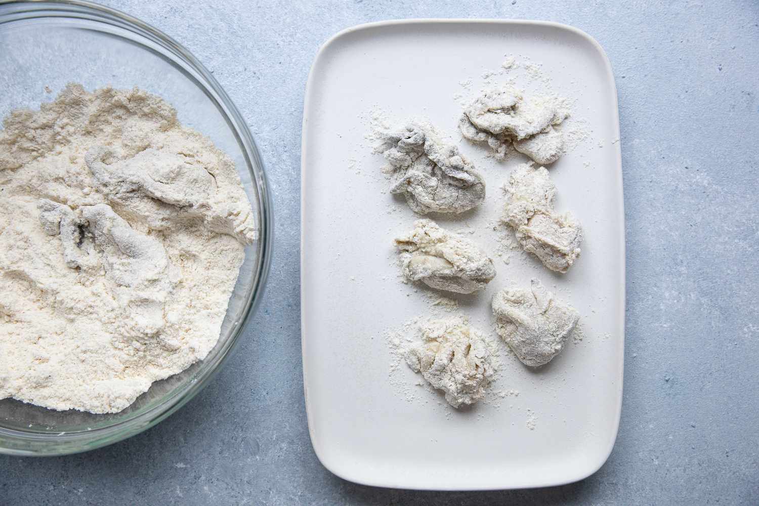 Dredged Oyster on a Platter Next to Bowl of Dry Dredging Mix with an Oyster in It for Oyster Po' Boy Recipe 