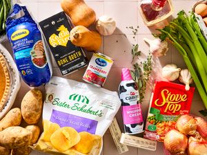 Assorted Thanksgiving food items including pie potatoes rolls cream and celery on a surface