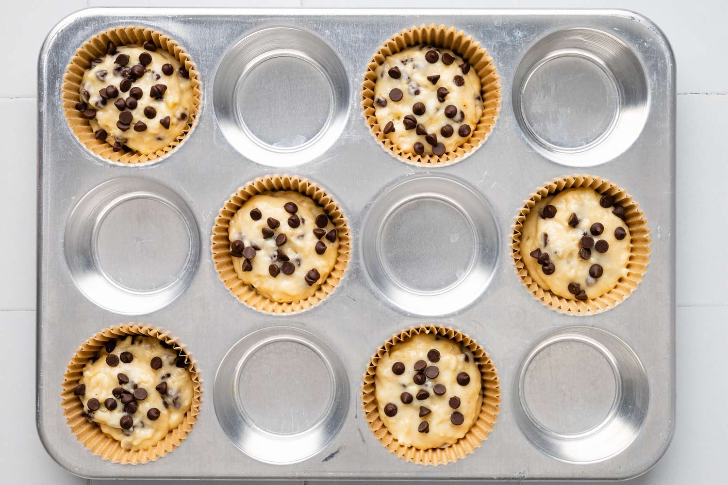Every Other Baking Tine Lined with Baking Cups and Filled with Banana Chocolate Chip Muffin Batter