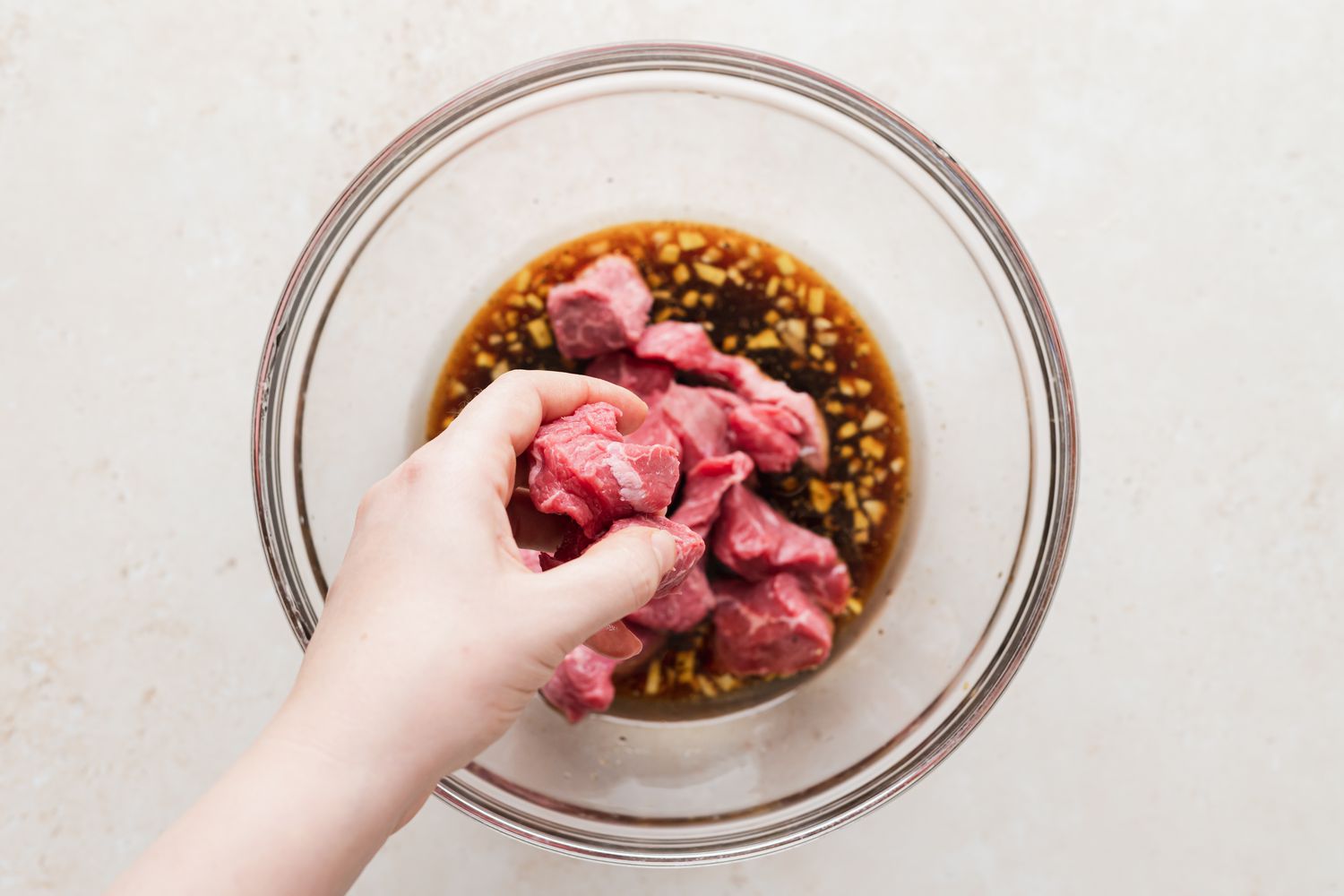 Glass bowl with marinade and beef inside to make shish kebab.