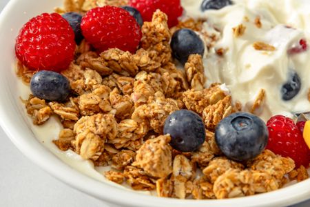 Closeup view of a bowl of granola topped with blueberries, strawberries and yogurt