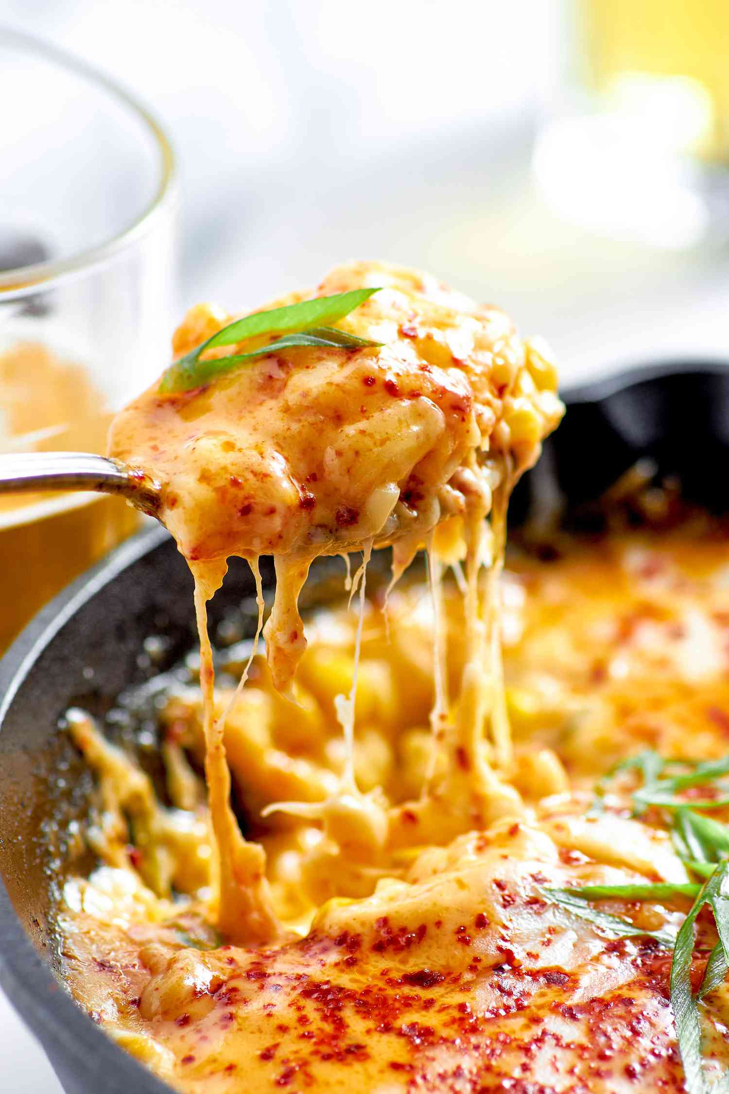Spoonful of Korean Corn Cheese Raised From Cast Iron Skillet With the Rest of the Cheese, Creating an Ooey Gooey Cheese Pull