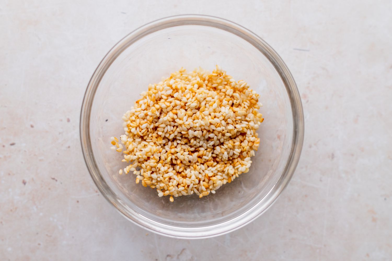 Toasted sesame seeds in a glass bowl to make a broccoli stir fry recipe.