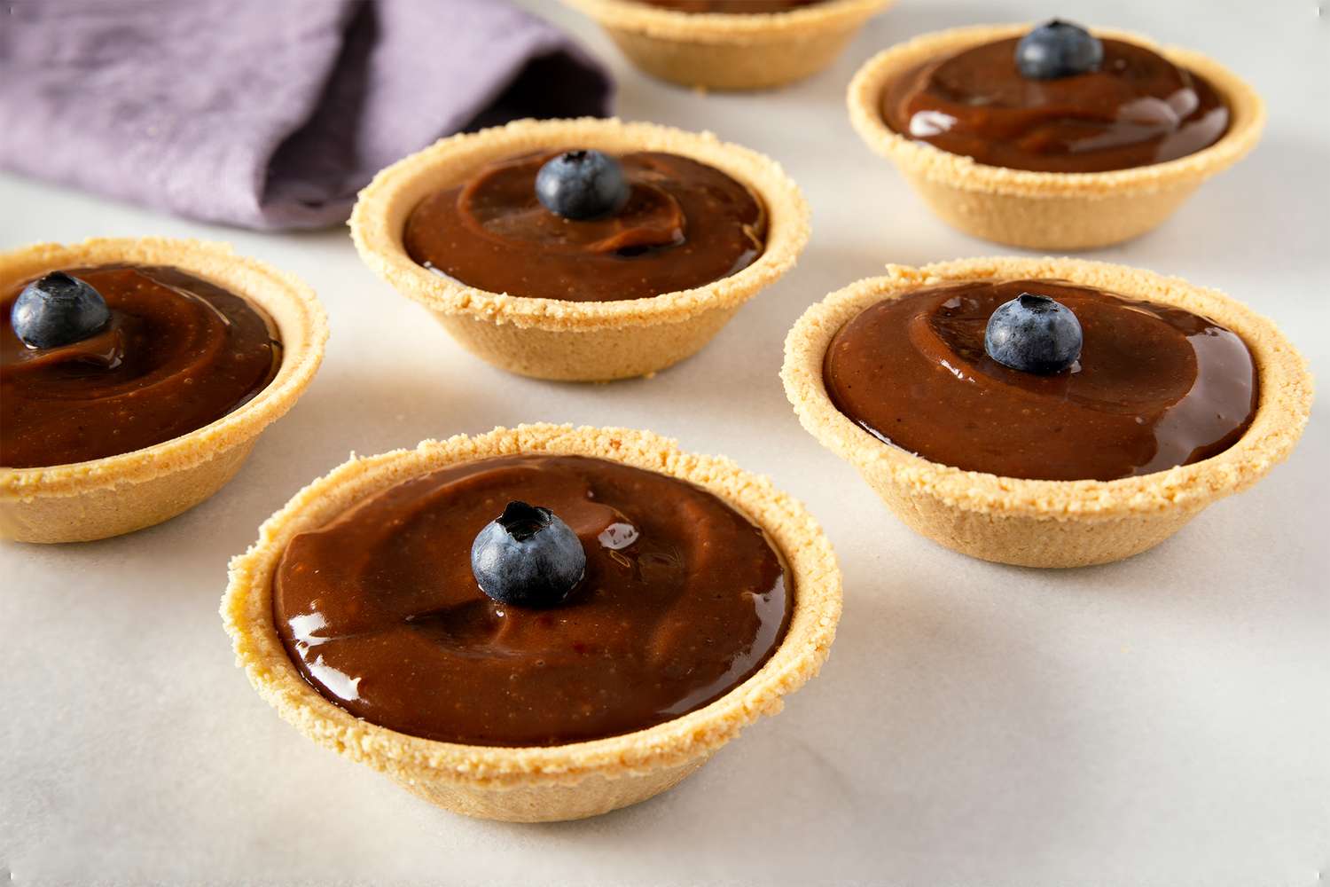 Small chocolate pudding pies topped with single blueberries arranged on a surface