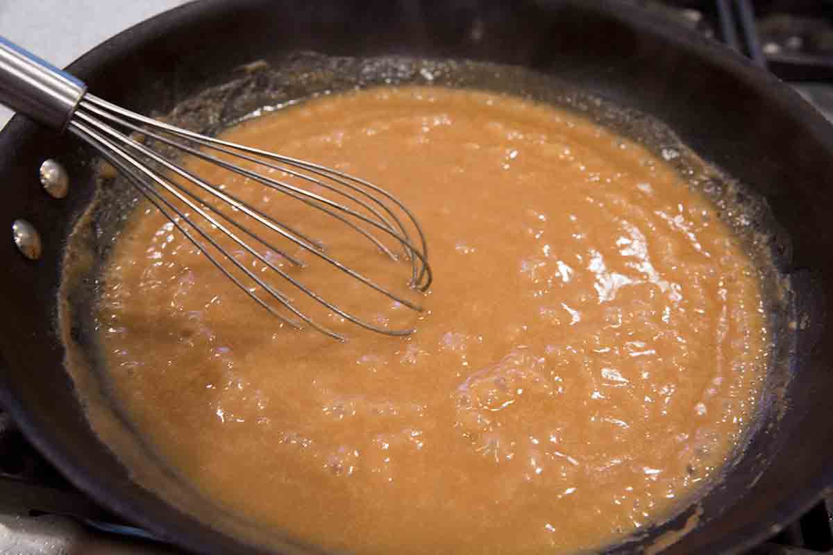 Stock being whisked into the meatball sauce