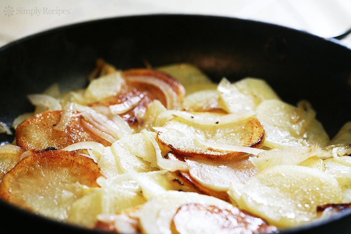 A skillet containing cooked potato slices and onions