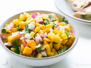 Mango Salsa in a white bowl with quesadillas in background
