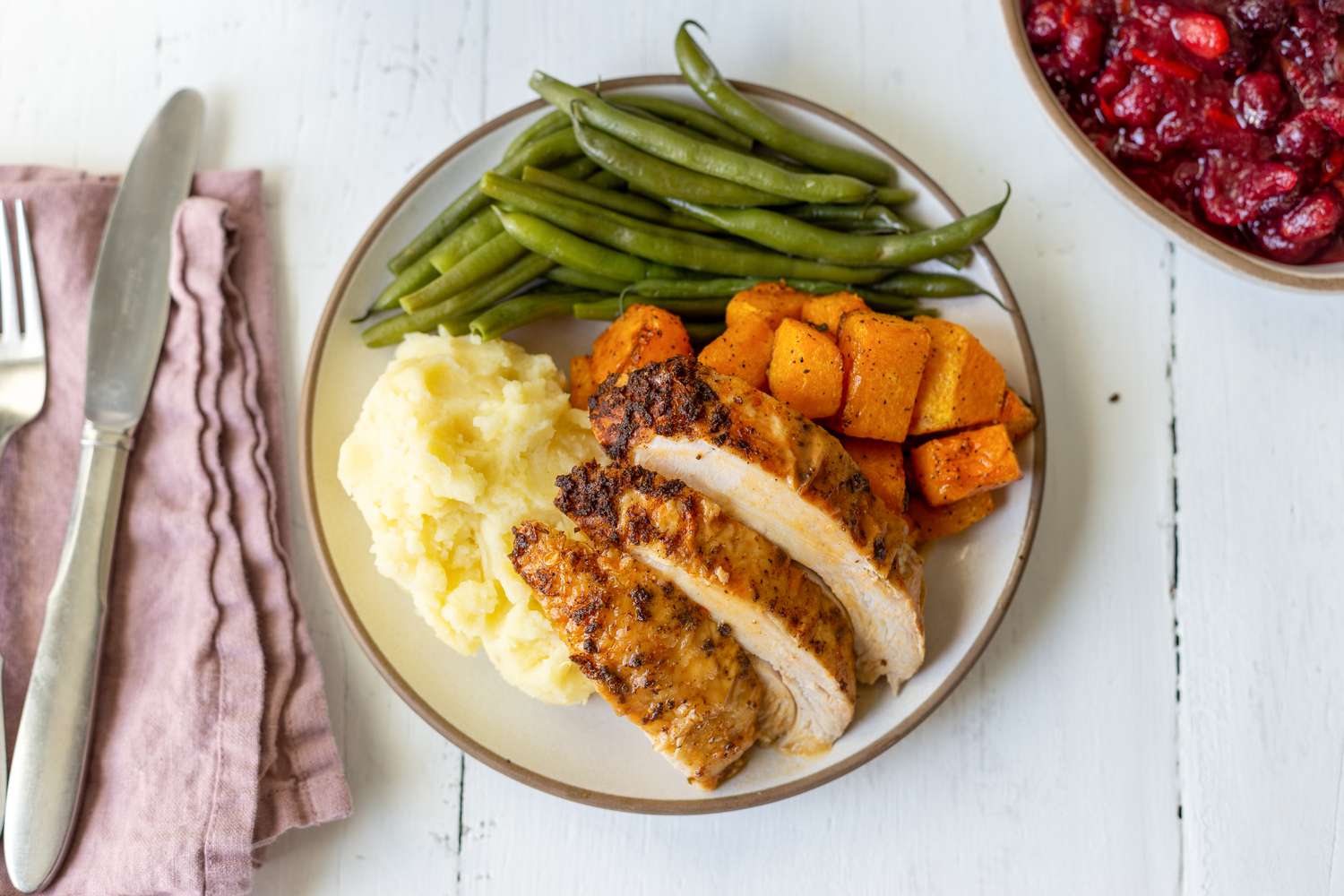 Simple instant pot turkey with gravy sliced and served on a plate with mashed potatoes, green beans, and sweet potatoes.