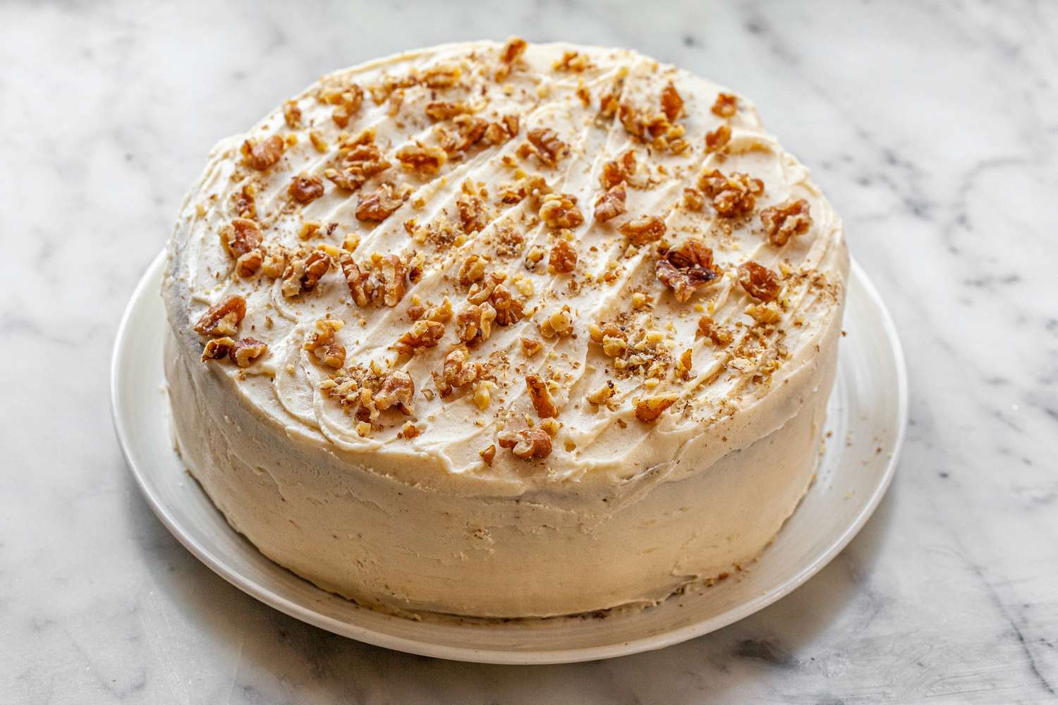 A whole carrot cake with pineapple on a platter.