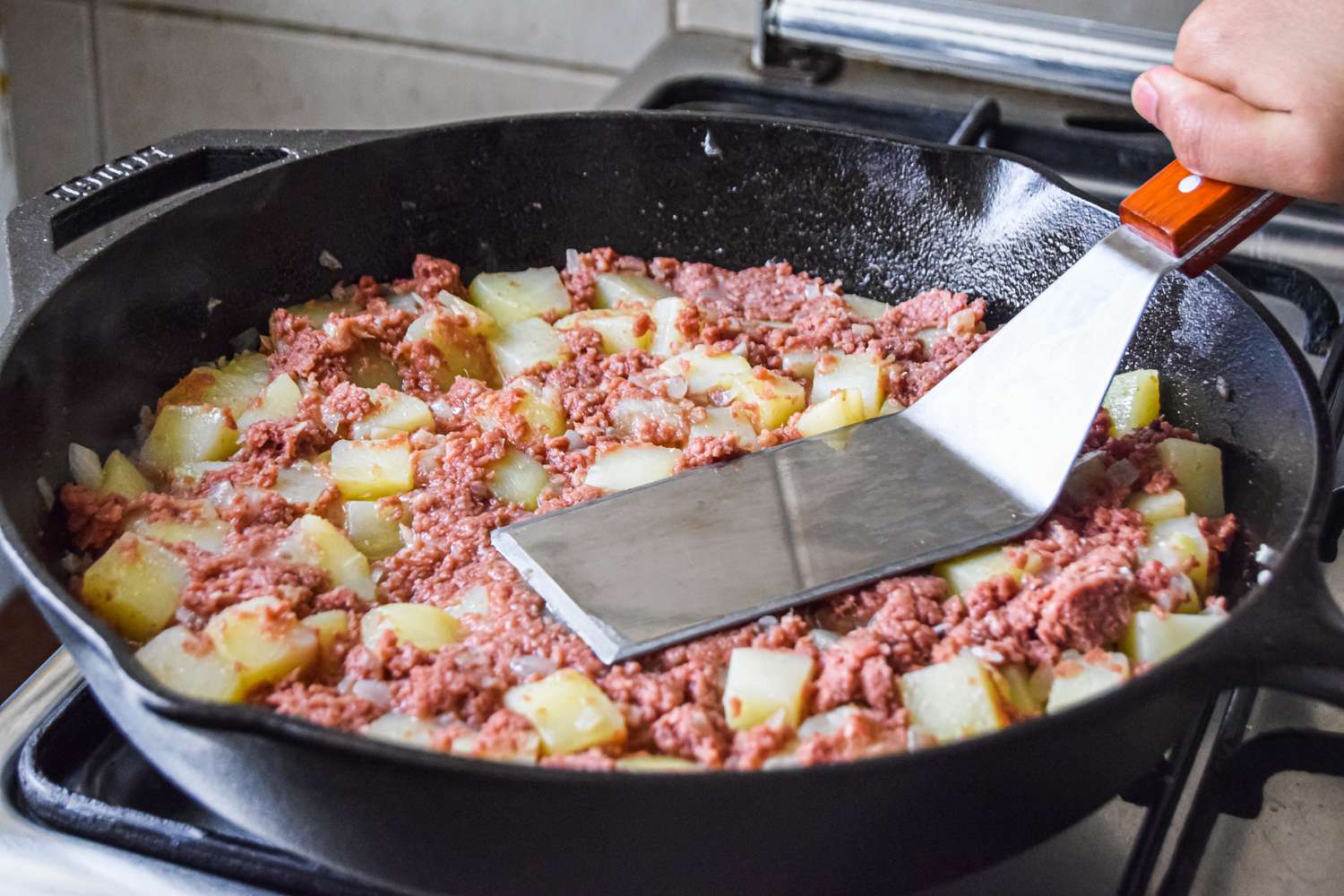 Corned Beef Hash Pressed Down into the Skillet Using a Spatula 