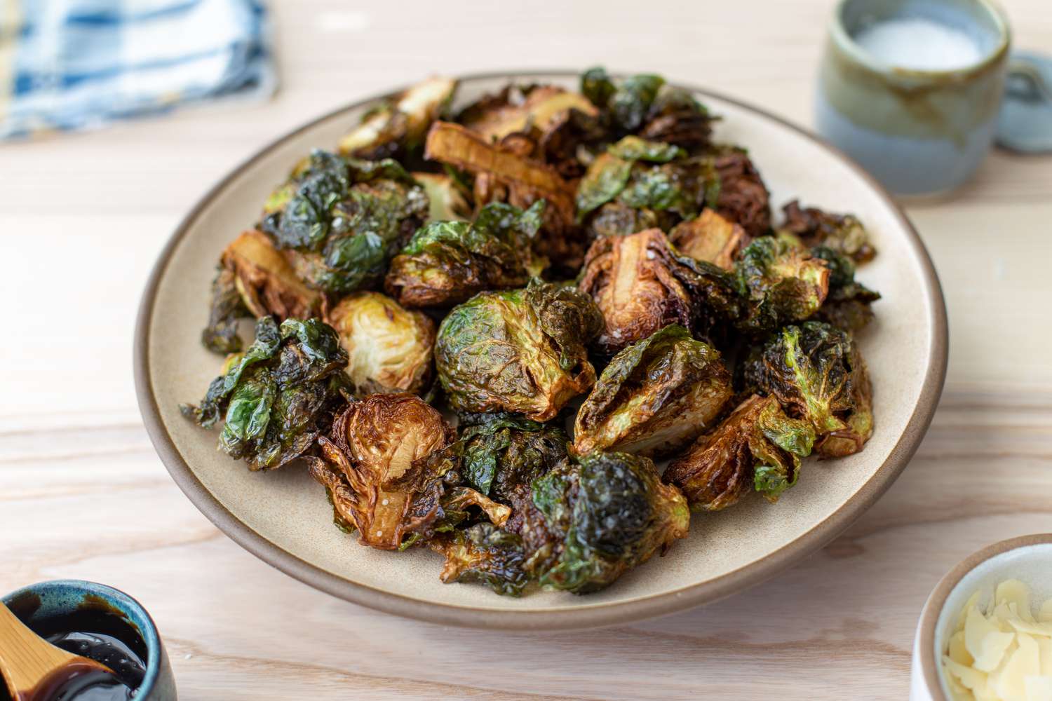 Bowl of Deep Fried Brussel Sprouts Next to Two Small Bowls (One with Balsamic Vinegar and Another with Shaved Parmesan)