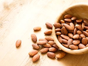 Almonds spilled from a wooden bowl on a table