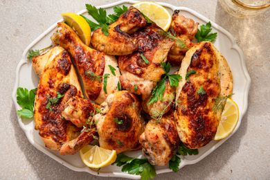 Ranch chicken topped with fresh herbs and lemon wedges on a platter