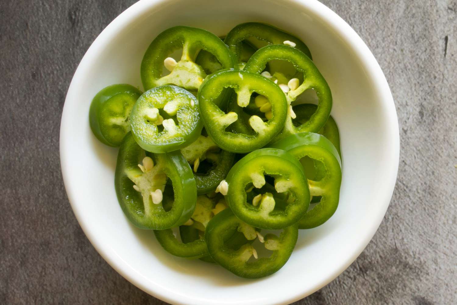 Sliced jalapeños in a small white bowl