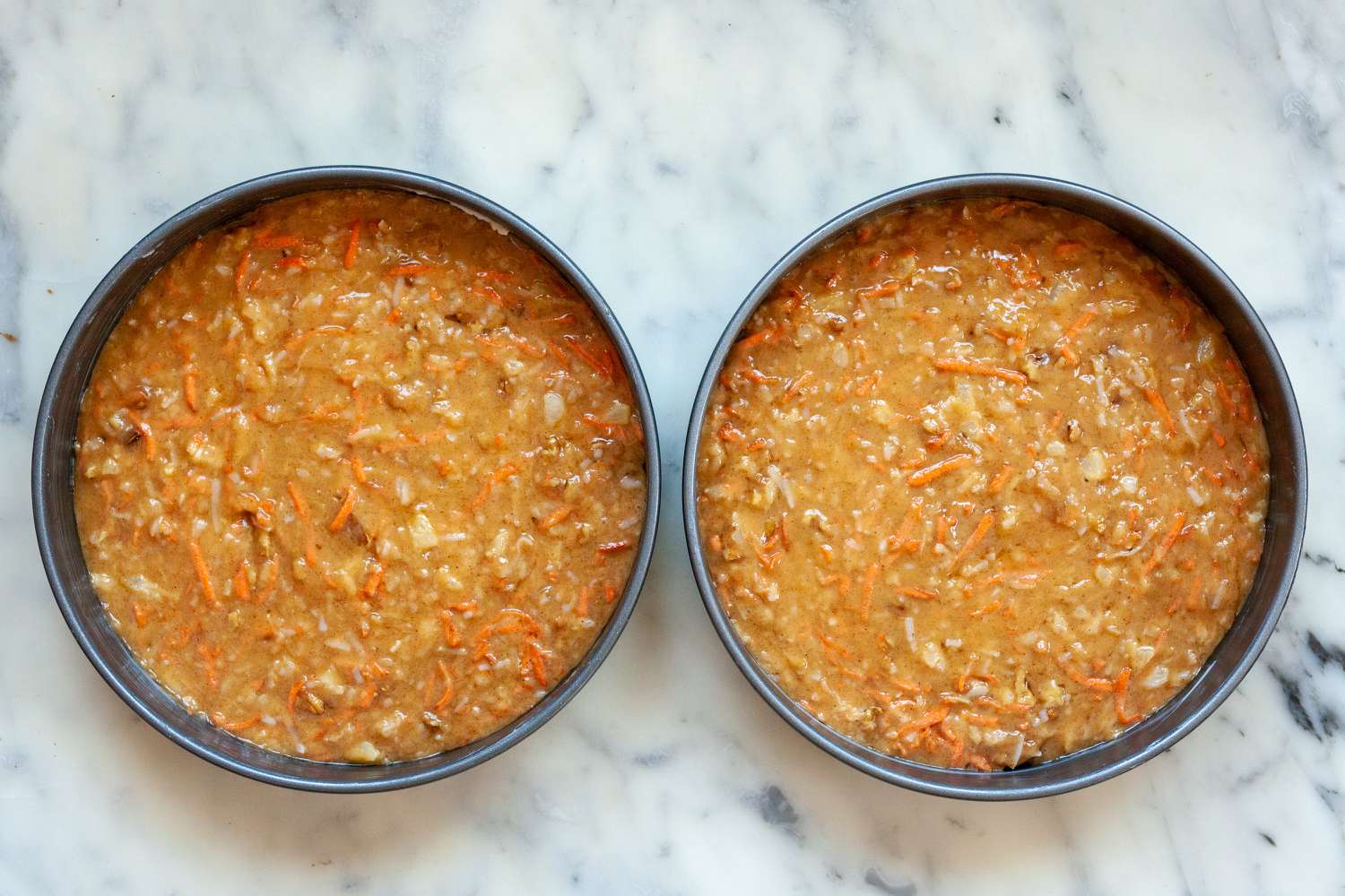 Two cake pans filled with batter to make the best carrot cake recipe.