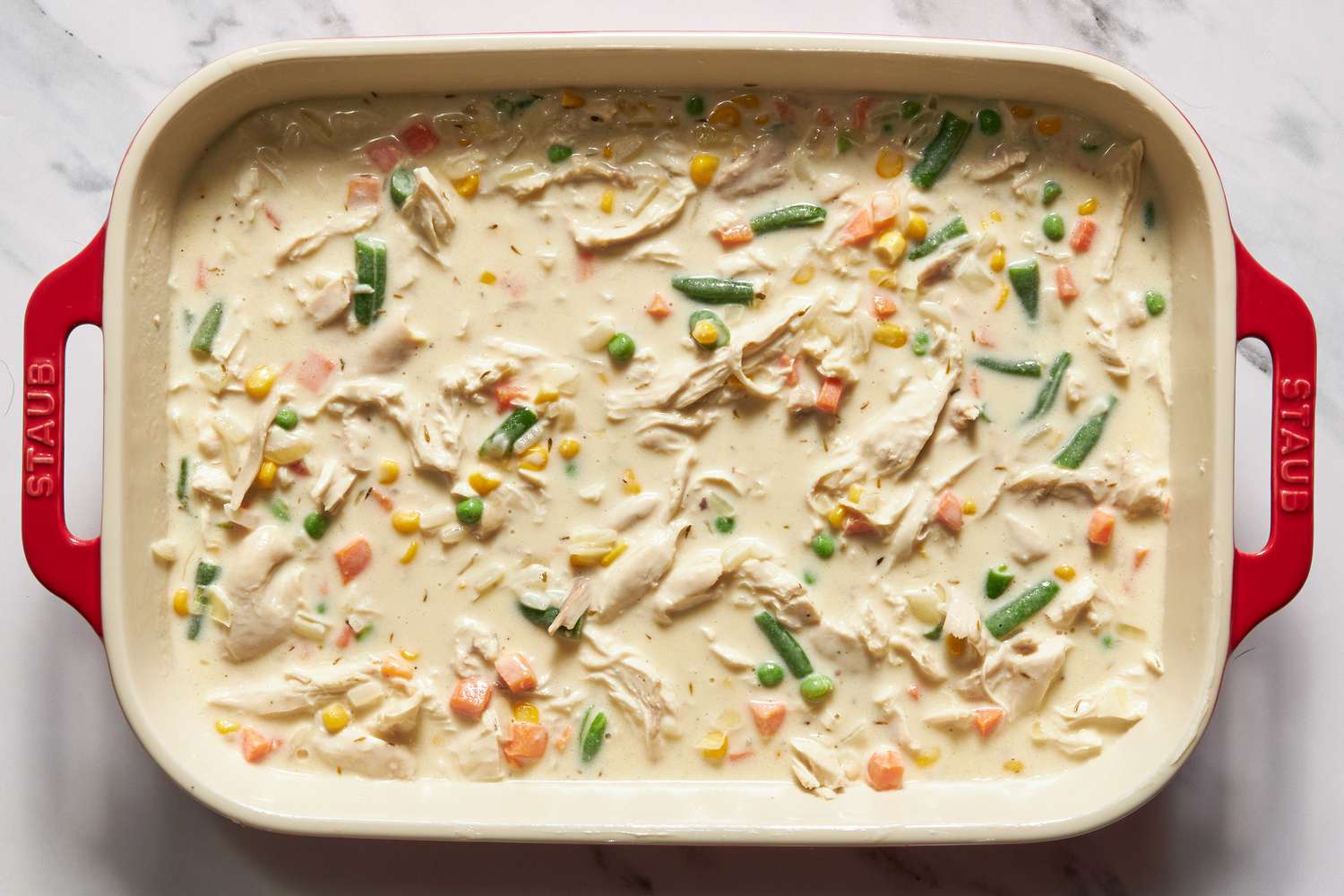 Chicken cobbler filling added to a casserole dish for chicken cobbler with cheddar bay biscuit top recipe