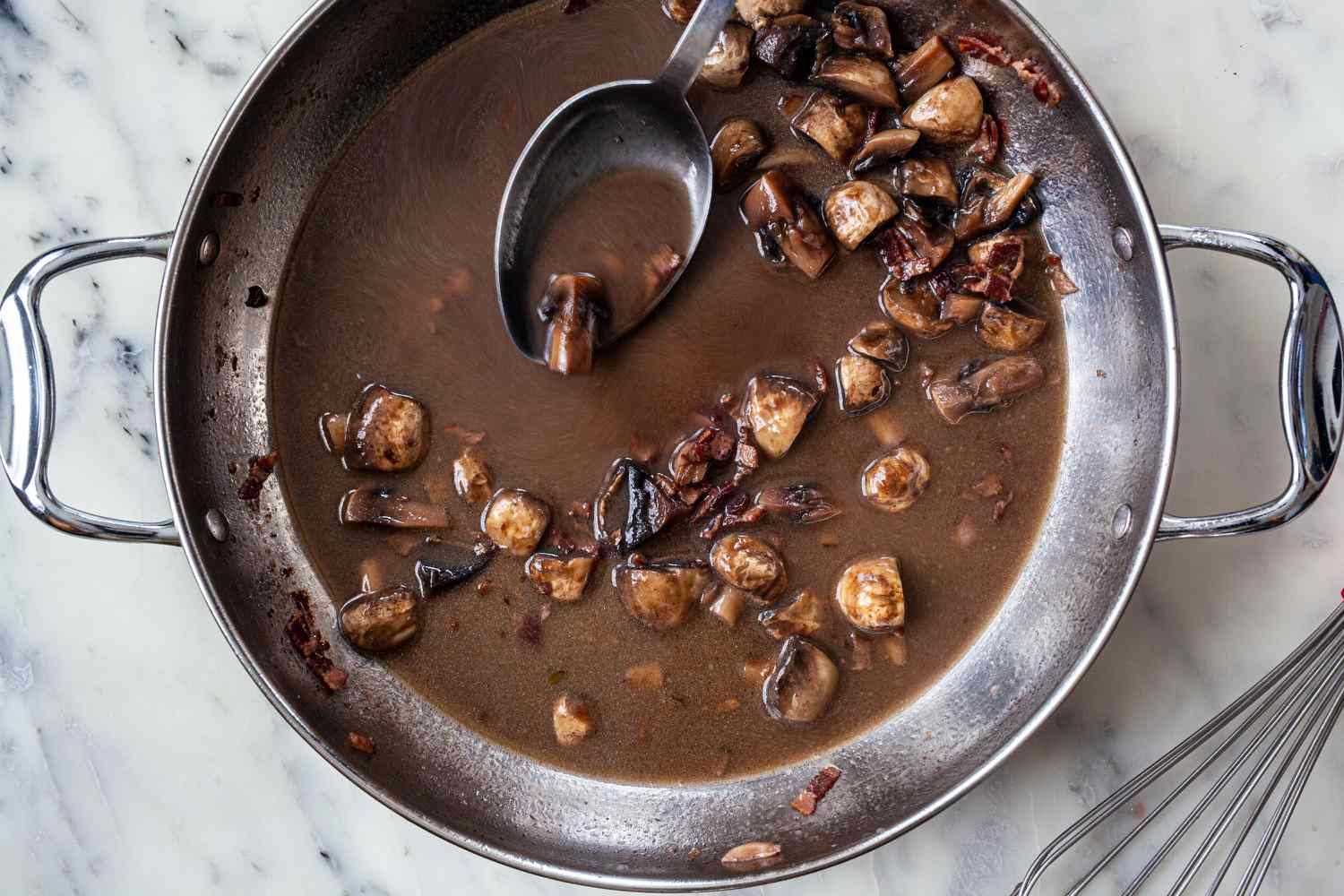 Spooning coco van sauce in a stockpot.