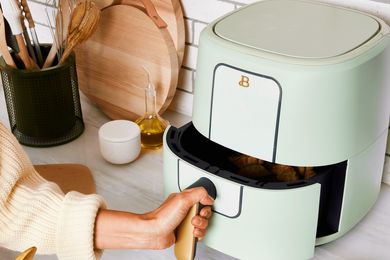 A person using an air fryer in a kitchen setting