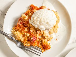 Plate with a serving of pumpkin dump cake topped with a scoop of ice cream fork placed on the side