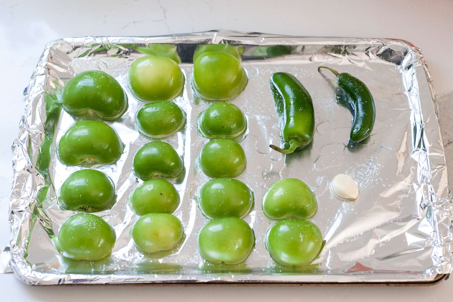 Tomatillos and Jalapeños on Baking Sheet Covered in Foil for Tomatillo Avocado Salsa Recipe