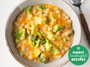 Broccoli and cheese white beans in a pale serving bowl with a spoon on the side